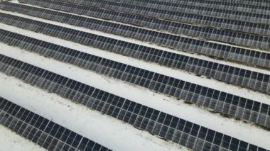 Aerial view of electrical power plant with solar panels covered with snow melting down in winter end for producing clean energy. Concept of low effectivity of renewable electricity in northern region.