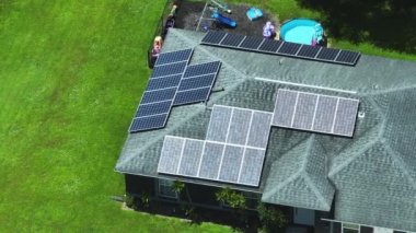 Temiz ekolojik elektrik enerjisi üretmek için mavi güneş fotovoltaik panelleri olan tipik Amerikan binasının çatısı. Emeklilik geliri kavramı için yenilenebilir elektriğe yatırım.