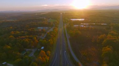 Aerial view of wide american freeway road with fast moving traffic cars and trucks in North Carolina golden fall season at sunset. Interstate transportation infrastructure in USA.