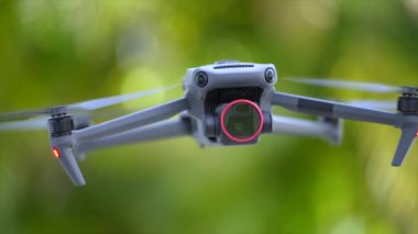 Drone quadcopter with digital camera and fast rotating propellers flying taking video and pictures.