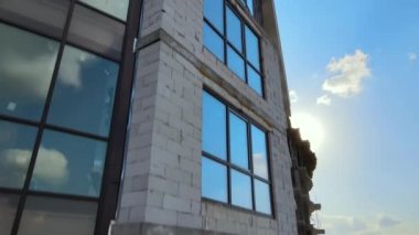 High residential apartment building with monolithic frame and glass windows under construction. Real estate development.