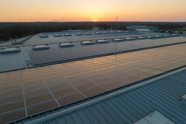 Mavi fotovoltaik güneş panelleri gün batımında temiz ekolojik elektrik üretmek için çatıya monte edildi. Yenilenebilir enerji konsepti üretimi.