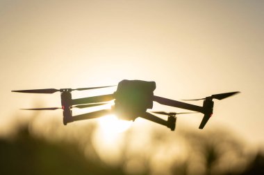 Drone quadcopter with digital camera and fast rotating propellers flying taking video and pictures.