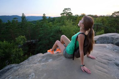 Yürüyüşçü kadın kayalık dağın tepesinde dinleniyor ve vahşi doğa yolculuğunun tadını çıkarıyor. Yüksek tepe yolundan geçen yalnız bir kadın gezgin. Sağlıklı yaşam tarzı kavramı.