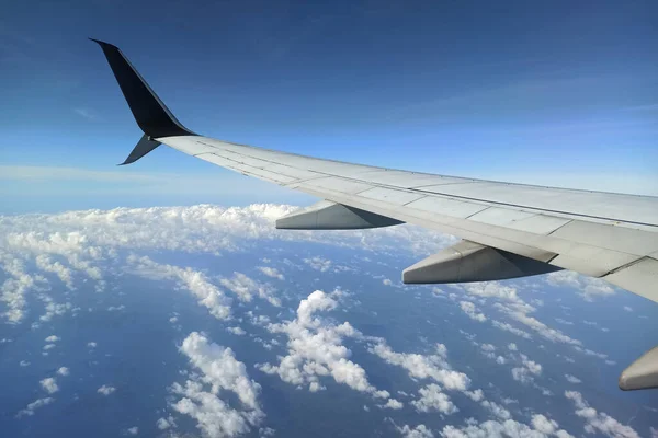 View through airplane window of commercial jet plane wing flying high in the sky. Air travelling concept.
