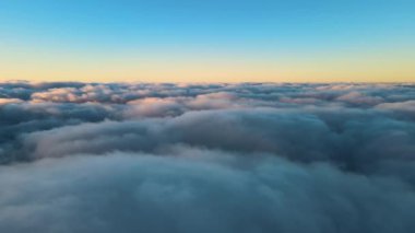 Yükseklerden gökyüzü manzarası. Akşamları yoğun, kabarık kümülüs bulutları uçuşuyor. Uçak penceresinden gün batımı inanılmaz..