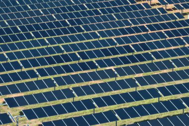 Temiz elektrik enerjisi üretmek için sıra sıra güneş fotovoltaik panelleri olan sürdürülebilir büyük elektrik santralinin havadan görünüşü. Sıfır emisyonlu yenilenebilir elektrik kavramı.