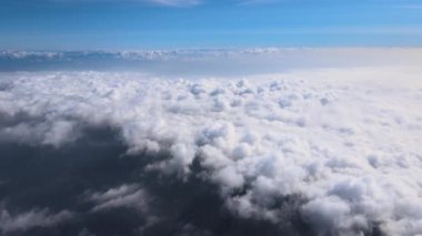 Dünya 'nın yüksek irtifasında, yağmur fırtınasından önce oluşan kabarık kümülüs bulutlarıyla kaplı uçak penceresinden hava görüntüsü.