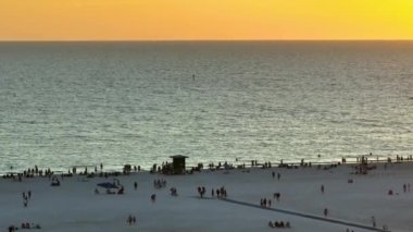 Aerial view of Siesta Key beach in Sarasota, USA. Many people enjoing vacation time swimming in gulf water and relaxing on warm Florida sun at sunset.
