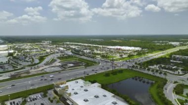 Aerial view of large multilane road with moving cars at intersection with traffic lights and large shopping malls.