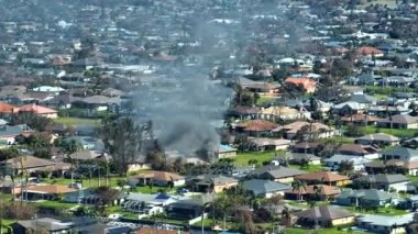 Burning residential house on fire with smoke and flames after short circuit spark ignited wooden roof damaged by hurricane Ian. Home disaster in Florida rural area.