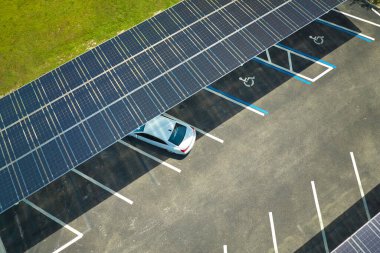 Aerial view of solar panels installed as shade roof over parking lot for parked cars for effective generation of clean electricity. Photovoltaic technology integrated in urban infrastructure.