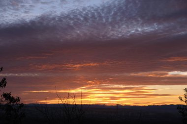 Parlak renkli günbatımı gökyüzü parlak pürüzsüz bulutlar aydınlatılıyor ve güneş ışığı ufka doğru yayılıyor..
