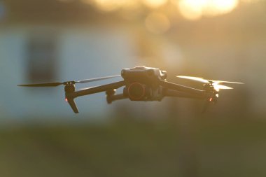 Drone quadcopter with digital camera and fast rotating propellers flying taking video and pictures.