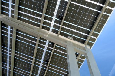Solar panels installed as shade roof over parking lot for parked electric cars for effective generation of clean electricity. Photovoltaic technology integrated in urban infrastructure.