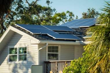 Standard american residential house with rooftop covered with solar photovoltaic panels for producing of clean electrical energy in suburban rural area. Concept of investment in autonomous home.