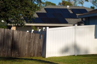 Bahçeyi çevreleyen yeşil çimlerde bahçe koruması ve mahremiyet için beyaz vinil çitler..