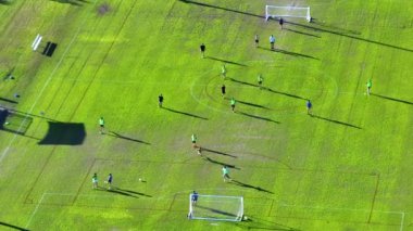 Çimenlerle kaplı spor stadyumunda futbol oynayan genç amatör sporcuların hava manzarası. Etkin yaşam biçimi kavramı.