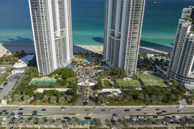 Sunny Isles Sahili 'nin havadan manzarası kalabalık sokak trafiği lüks oteller ve Atlantik Okyanusu kıyısındaki apartmanlar. Güney Florida 'daki Amerikan turizm altyapısı.