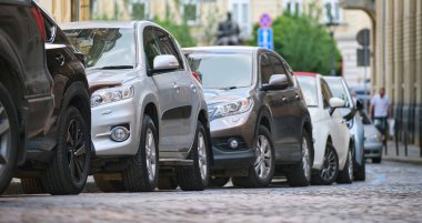 Sokak kenarında park halindeki arabalarla şehir trafiği.