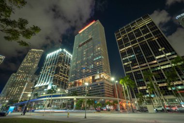 Florida 'da Miami Brickell' in şehir merkezinin gece manzarası. Modern Amerikan megapolis 'inde yüksek gökdelen binaları ve caddelerde araba izleri ve metro trafiği var..