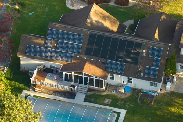 Big new residential house in USA with rooftop covered with solar photovoltaic panels for producing of clean ecological electrical energy in suburban rural area. Concept of autonomous home.