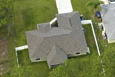 Tipik modern Amerikan özel evinin çatısı asfalt kiremitlerle ve bahçedeki yeşil çimlerle kaplı..