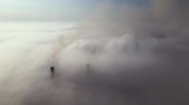 Coal power plant high pipes with black smoke moving upwards over clouds polluting atmosphere. Production of electrical energy with fossil fuel concept.