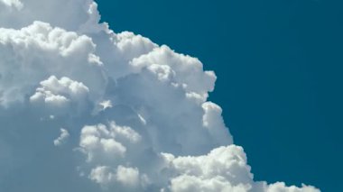 Beyaz kabarık kümülüs bulutlarının zamanı yaz mavi gökyüzünde şekilleniyor. Hareket eden ve değişen bulutlu hava durumu.