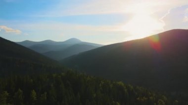 Parlak sisli sabahın hava manzarası sonbahar gündoğumunda dağlık orman ağaçlarıyla birlikte karanlık tepelerin üzerinde. Şafak vakti vahşi ormanın güzel manzarası.