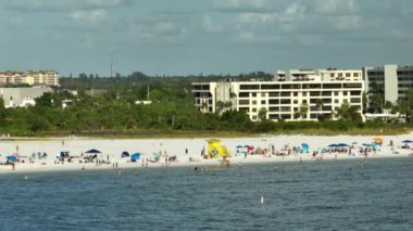 Sarasota, ABD 'de yumuşak beyaz kumlu ünlü Siesta Key plajı. Birçok insan sıcak körfez sularında yıkanarak ve sıcak Florida güneşi altında bronzlaşarak tatil yapıyor..
