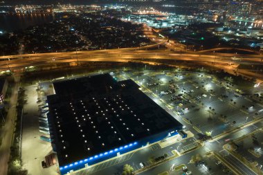 Aerial night view of many cars parked on parking lot with lines and markings for parking places and directions. Place for vehicles in front of a grocery mall store.