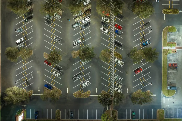 Aerial night view of many cars parked on parking lot with lines and markings for parking places and directions. Place for vehicles in front of a grocery mall store.