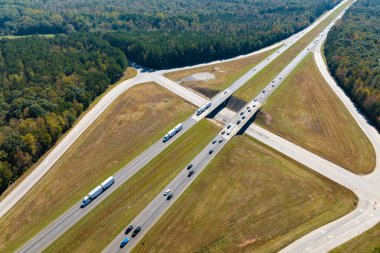 Aerial view of freeway overpass junction with fast moving traffic cars and trucks in american rural area. Interstate transportation infrastructure in USA.
