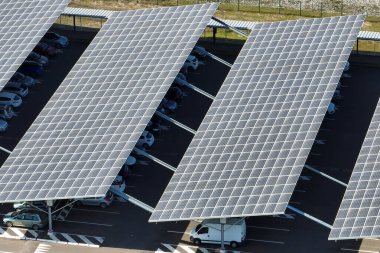 Güneş panellerinin hava görüntüsü park yerinin üzerine gölge çatısı olarak yerleştirilmiş ve temiz elektriğin etkin üretimi için park edilmiş arabalar var. Fotovoltaik teknoloji şehir altyapısına entegre edildi.