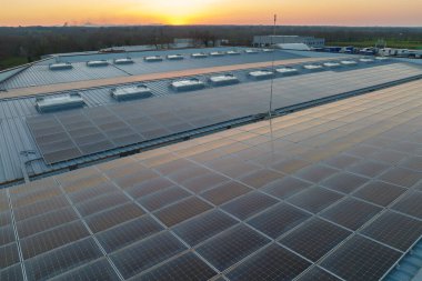 Sanayi binasının çatısına yeşil ekolojik elektrik üretmek için monte edilmiş mavi fotovoltaik panelli güneş enerjisi santralinin hava görüntüsü. Sürdürülebilir enerji konsepti üretimi.