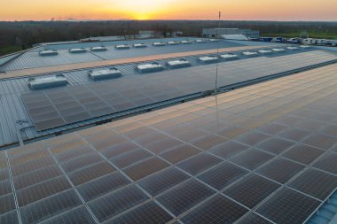 Sanayi binasının çatısına yeşil ekolojik elektrik üretmek için monte edilmiş mavi fotovoltaik panelli güneş enerjisi santralinin hava görüntüsü. Sürdürülebilir enerji konsepti üretimi.