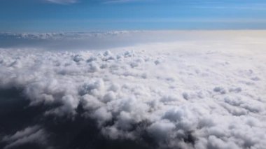 Dünya 'nın yüksek irtifasındaki uçak penceresinden hava manzarası beyaz kabarık kümülüs bulutlarıyla kaplı..