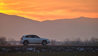 Gün batımında şehirlerarası yolda hızla giden bir SUV arabası. Akşamları otoyol trafiği.