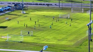 Çimenlerle kaplı spor stadyumunda futbol oynayan genç amatör sporcuların hava manzarası. Etkin yaşam biçimi kavramı.