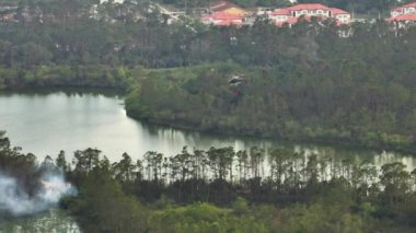 İtfaiye helikopteri Florida orman ormanlarında yangın söndürmek için su dolduruyor. Acil servis helikopteri ormanda yangın çıkarmaya çalışıyor..