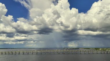 Stormy clouds forming from evaporating humidity of ocean water before thunderstorm over traffic bridge connecting Punta Gorda and Port Charlotte over Peace River. Bad weather conditions for driving.