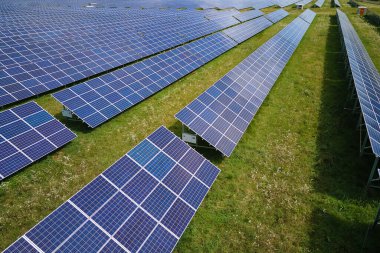 Temiz elektrik enerjisi üretmek için birçok sıra güneş fotovoltaik paneli bulunan sürdürülebilir büyük elektrik santralinin havadan görünüşü. Sıfır emisyon kavramı ile yenilenebilir elektrik.