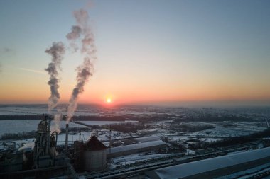 Gün batımında endüstriyel üretim alanında yüksek beton yapılı çimento fabrikası kulesinin havadan görüntüsü. Üretim ve küresel sanayi kavramı.