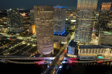 Florida, ABD 'deki Tampa şehrinin şehir merkezindeki hava manzarası. Parlak ışıklandırılmış yüksek gökdelen binalar, yaya nehir yolu ve modern Amerikan şehir merkezinde trafik..