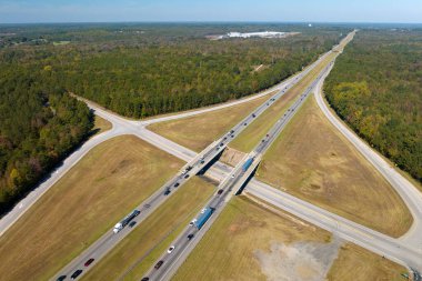 View from above of busy american highway with fast moving traffic between woods. Interstate transportation concept.