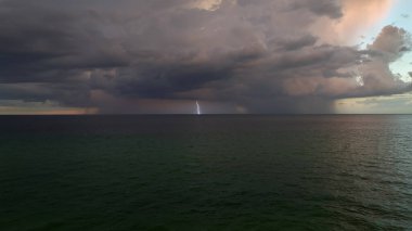 Şiddetli yağış mevsiminde akşam vakti deniz yüzeyinde kasvetli gökyüzünde kara fırtınalı bulutlar oluşur..