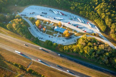 Top view of large rest area near busy multilane american freeway with fast moving cars and trucks. Recreational resting place during interstate traveling.