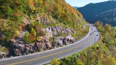 Aerial view of highway road in North Carolina through Appalachian mountains in golden fall season with fast moving trucks and cars. Interstate transportation concept.
