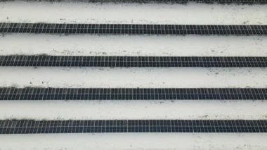 Aerial view of snow melting from covered solar photovoltaic panels at sustainable electric power plant for producing clean electrical energy. Low effectivity of renewable electricity in winter.